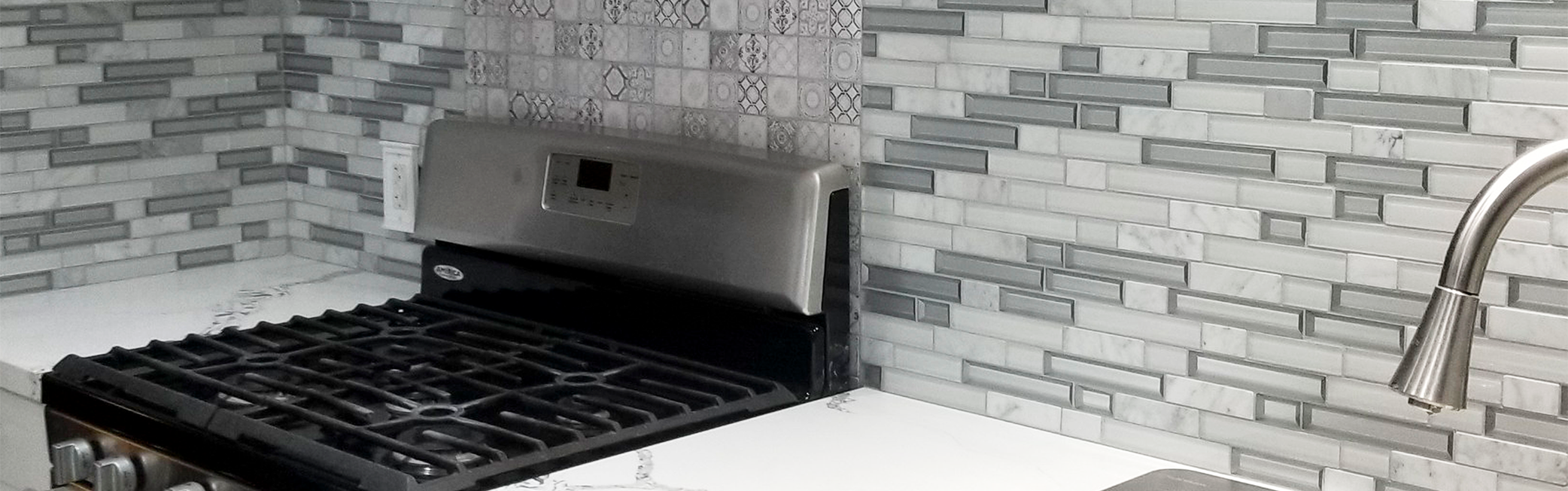 Artistically designed kitchen wall in various shades of gray, shapes and patterns of tile